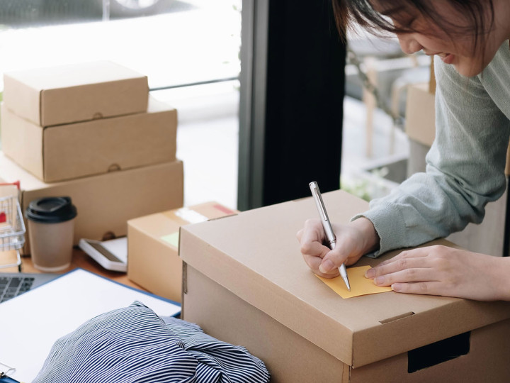 Shipping shopping online ,young start up small business owner writing address on cardboard box at workplace. seller prepare parcel boxs of product for deliver to customer.Online selling or e-commerce